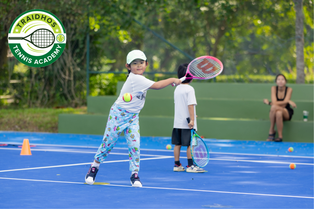 A junior student playing tennis on an outdoor court at Prem International School